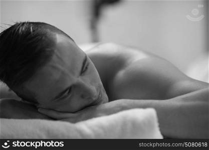 attractive handsome man resting in a spa massage center, lying on table relaxing closed eyes concept of men beauty health care