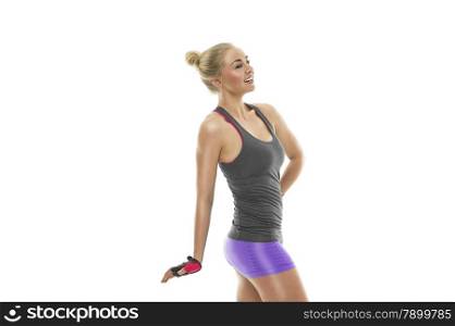Attractive happy athletic young blond woman with a fit toned body posing sideways with her hand on her hip showing off her sexy muscular physique, isolated on white