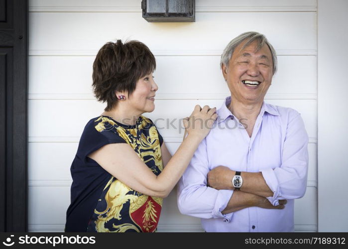 Attractive Happy Chinese Couple Enjoying Their House Outside.