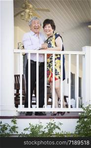 Attractive Happy Chinese Couple Enjoying Their House Outside.