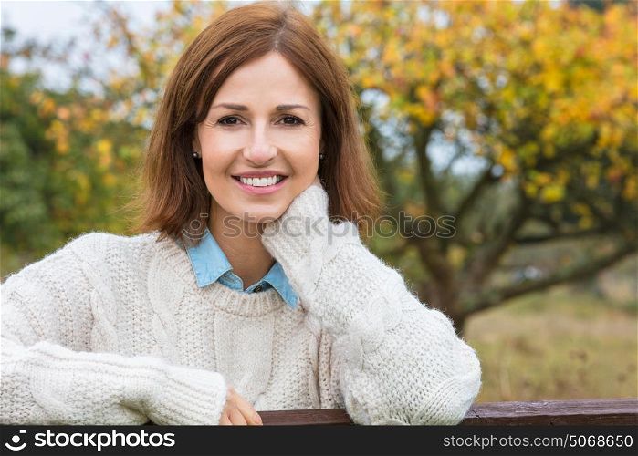 Attractive happy thoughtful middle aged woman leaning resting on fence in the countryside