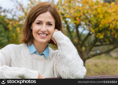 Attractive happy thoughtful middle aged woman leaning resting on fence in the countryside. Attractive Happy Middle Aged Woman Resting on Fence