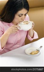 Attractive Hispanic woman drinking cappuccino.