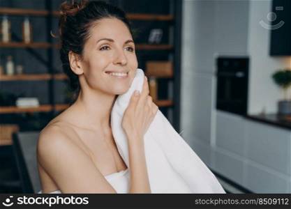 Attractive hispanic woman is wiping face with towel after washing. Happy girl takes shower at home and doing skin care. Hygiene, freshness and female spa procedures. Beauty routine.. Attractive hispanic woman is wiping face with towel after shower at home. Beauty routine.