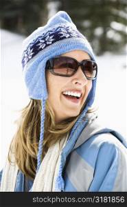 Attractive laughing mid adult Caucasian blond woman wearing blue ski cap and sunglasses.