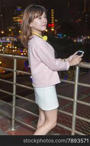Attractive Malaysian Woman With Yellow Headphones holding cellphone