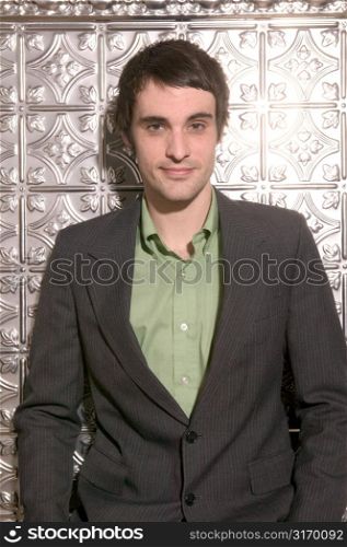 Attractive Male Model Posing Against An Ornately Tiled Silver Wall