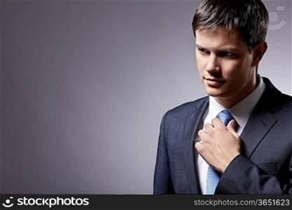 Attractive man in a suit straightens his tie