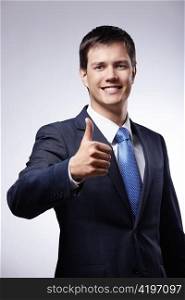 Attractive man in a suit with a thumb up on a gray background