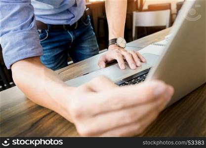 Attractive man in casual business sitting at a table working on his laptop computer at home office in front of a window.
