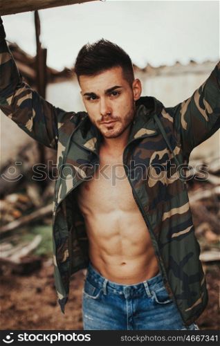 Attractive man showing his abs under a camouflage jacket