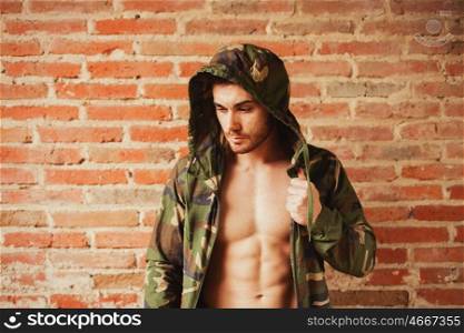 Attractive man showing his abs under a camouflage jacket