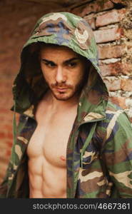 Attractive man showing his abs under a camouflage jacket