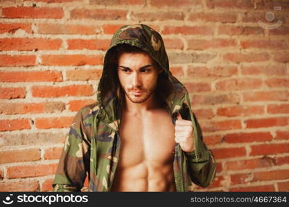 Attractive man showing his abs under a camouflage jacket