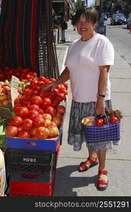 Attractive mature woman buying vegetables at fruit stand