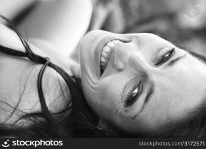 Attractive mid adult Caucasian woman lying on back smiling and looking at viewer.