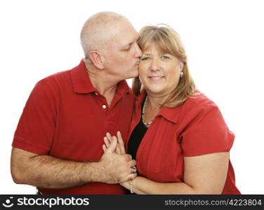 Attractive middle-aged couple in love. He&rsquo;s kissing her on the cheek. Isolated on white.