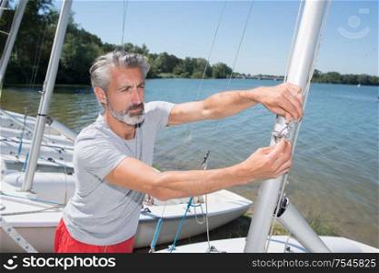 attractive middle-aged man preparing sport sailboat