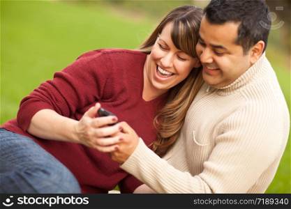 Attractive Mixed Race Couple Enjoying Their Camera Phone in the Park.