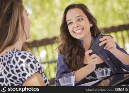 Attractive Mixed Race Girls Smiling and Talking While Working on Smart Mobile Phone and Tablet Computer.