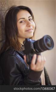 Attractive Mixed Race Young Adult Female Photographer Against Wall Holding Camera.