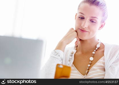 Attractive office worker sitting at desk. Attractive woman sitting at desk in office holding mobile phone