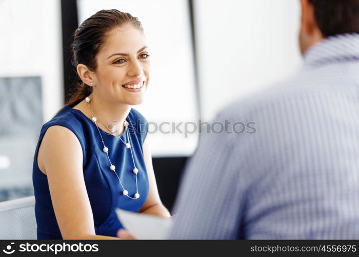 Attractive office worker sitting at desk. Attractive woman sitting at desk in office with her colleague