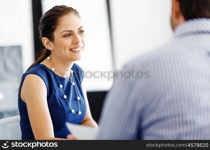 Attractive office worker sitting at desk. Attractive woman sitting at desk in office with her colleague