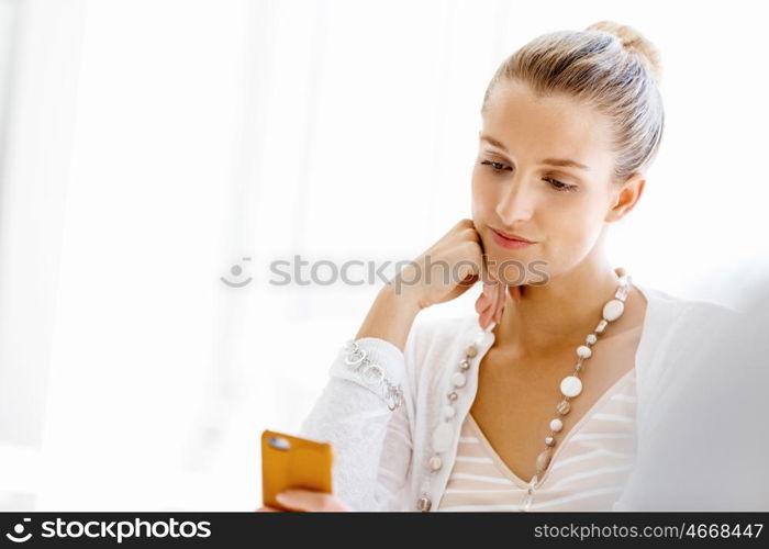 Attractive office worker sitting at desk. Attractive woman sitting at desk in office holding mobile phone