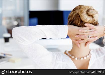 Attractive office worker sitting at desk. Attractive woman sitting at desk in office view from back