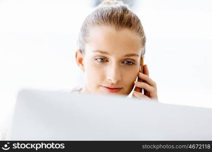 Attractive office worker sitting at desk. Attractive woman sitting at desk in office holding mobile phone