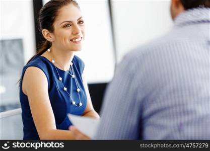 Attractive office worker sitting at desk. Attractive woman sitting at desk in office with her colleague