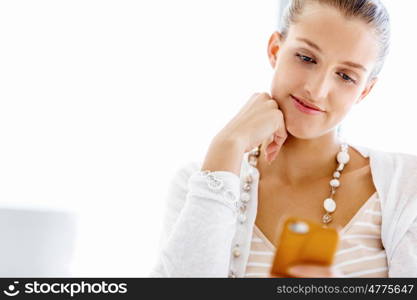 Attractive office worker sitting at desk. Attractive woman sitting at desk in office holding mobile phone