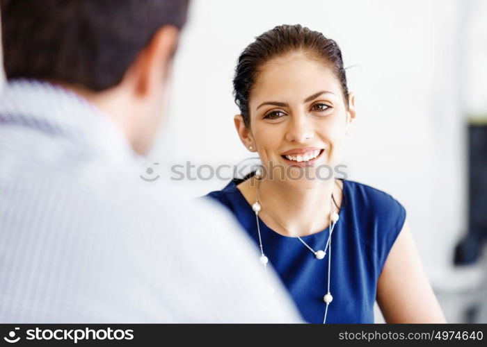 Attractive office worker sitting at desk. Attractive woman sitting at desk in office with her colleague