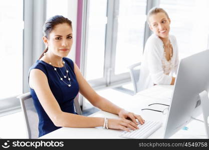 Attractive office worker sitting at desk. Attractive woman sitting at desk in office