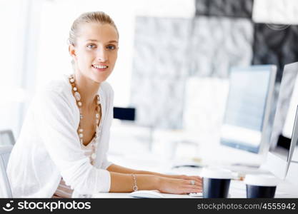 Attractive office worker sitting at desk. Attractive woman sitting at desk in office