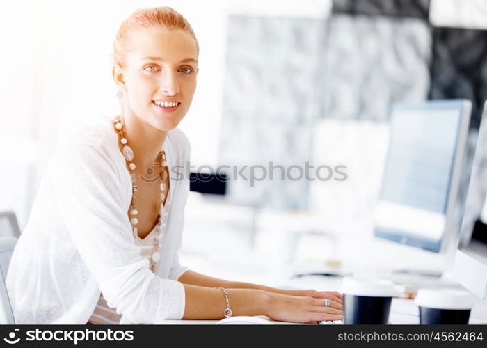 Attractive office worker sitting at desk. Attractive woman sitting at desk in office