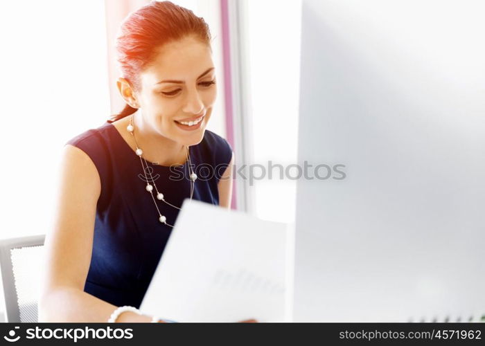 Attractive office worker sitting at desk. Attractive woman sitting at desk in office