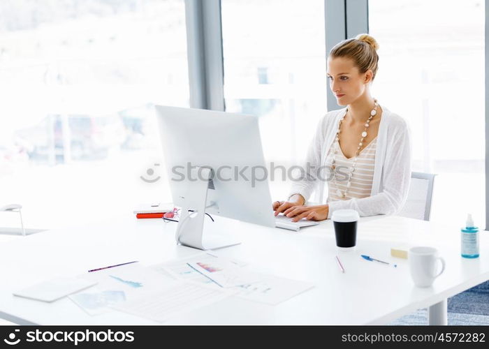 Attractive office worker sitting at desk. Attractive woman sitting at desk in office