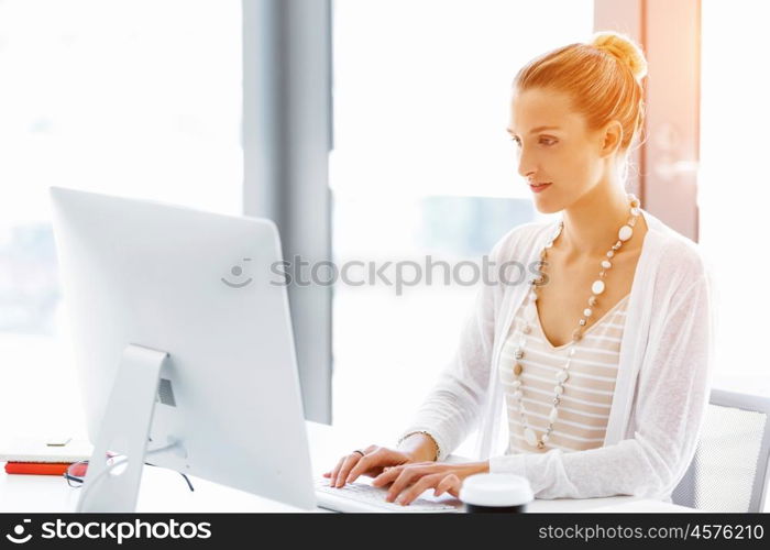 Attractive office worker sitting at desk. Attractive woman sitting at desk in office