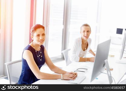 Attractive office worker sitting at desk. Attractive woman sitting at desk in office