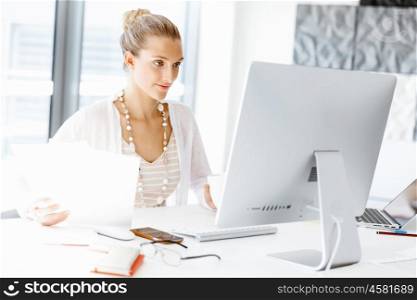 Attractive office worker sitting at desk. Attractive woman sitting at desk in office
