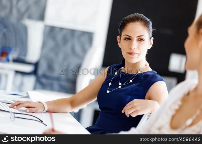 Attractive office worker sitting at desk. Attractive woman sitting at desk in office