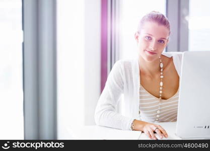 Attractive office worker sitting at desk. Attractive woman sitting at desk in office