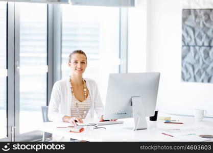 Attractive office worker sitting at desk. Attractive woman sitting at desk in office