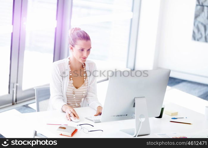 Attractive office worker sitting at desk. Attractive woman sitting at desk in office