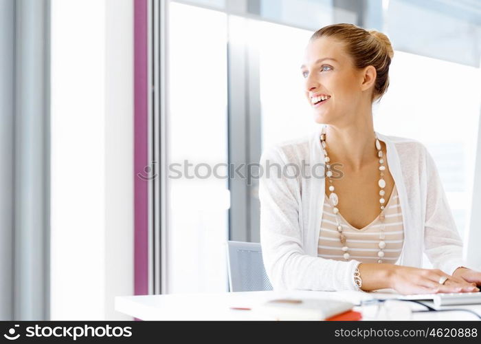 Attractive office worker sitting at desk. Attractive woman sitting at desk in office