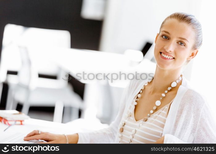 Attractive office worker sitting at desk. Attractive woman sitting at desk in office