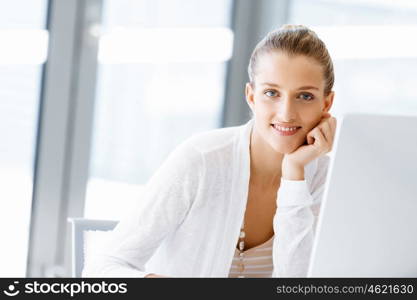 Attractive office worker sitting at desk. Attractive woman sitting at desk in office