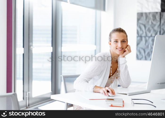 Attractive office worker sitting at desk. Attractive woman sitting at desk in office